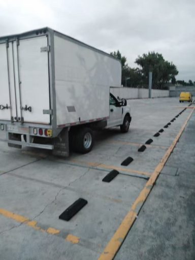 Camión de carga blanco estacionado en un área con líneas amarillas y grises.